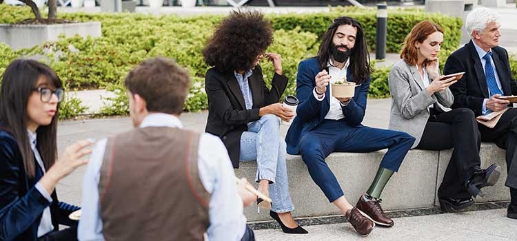 six coworkers eating outside talking 