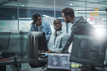 cybersecurity professionals consult at one desk over problem